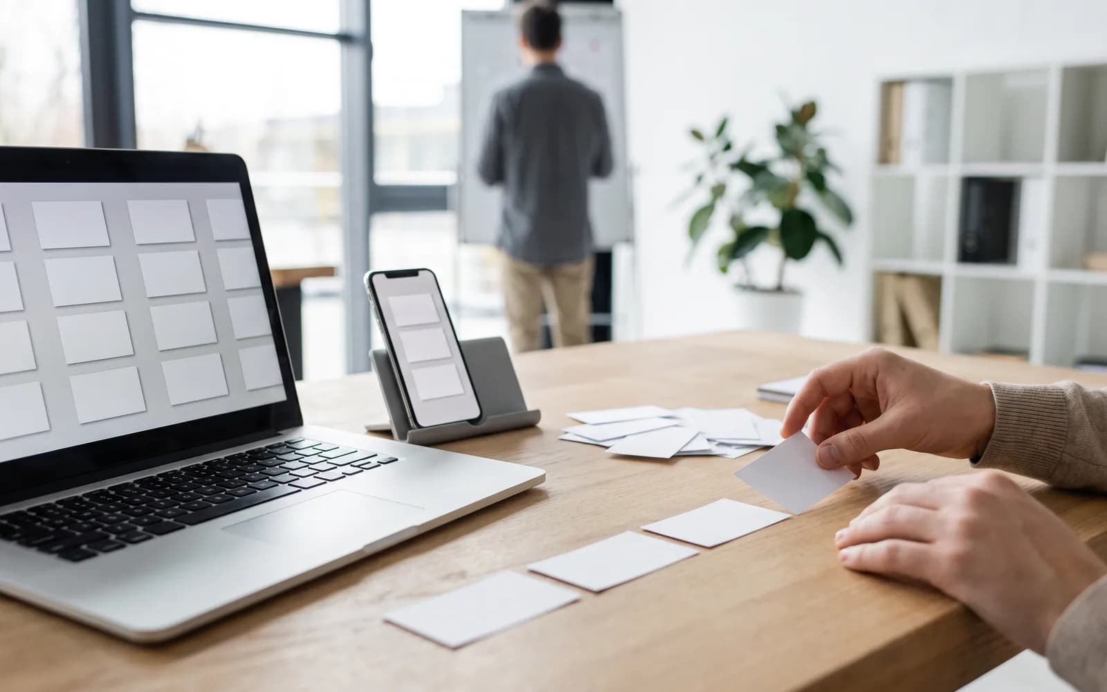 Heller Arbeitsplatz mit Laptop und Smartphone, geordnete Aufgabenkarten – Work-Orchestrierung mit Prakti